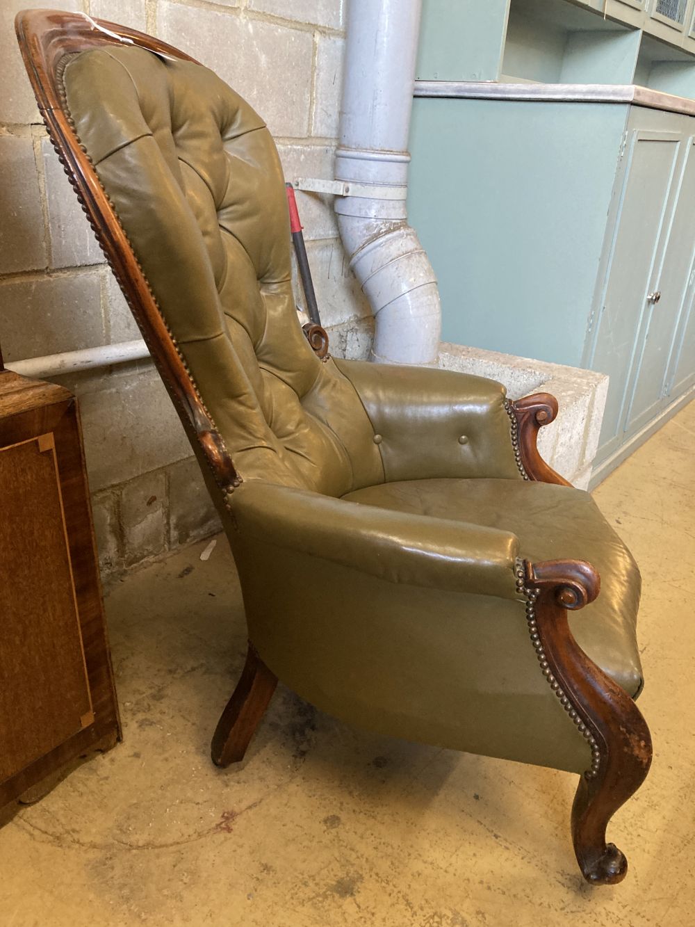 A Victorian carved and moulded showood frame spoonback armchair on scrolled legs, upholstered in buttoned green hide, width 68cm, heigh